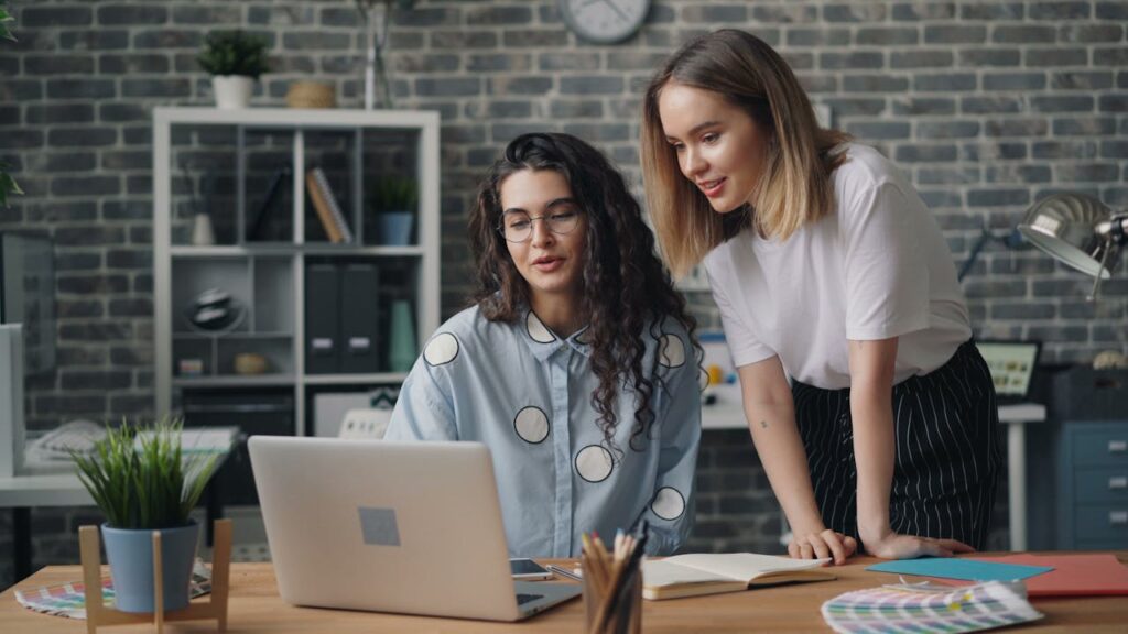 Two women working on a laptop in an office