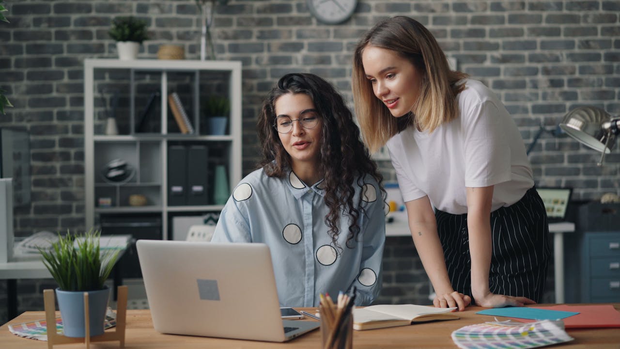 Two women working on a laptop in an office