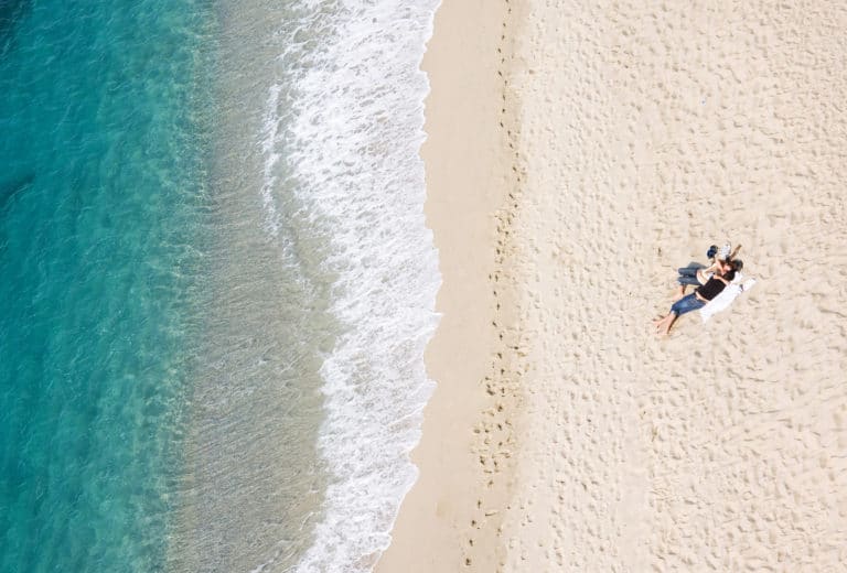 View of young couple resting on tropical beach, lots of copyspac