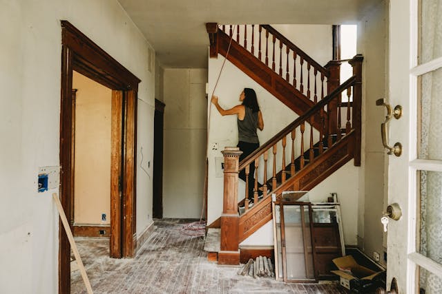 A Woman in Gray Tank Top Standing on Wooden Staircase