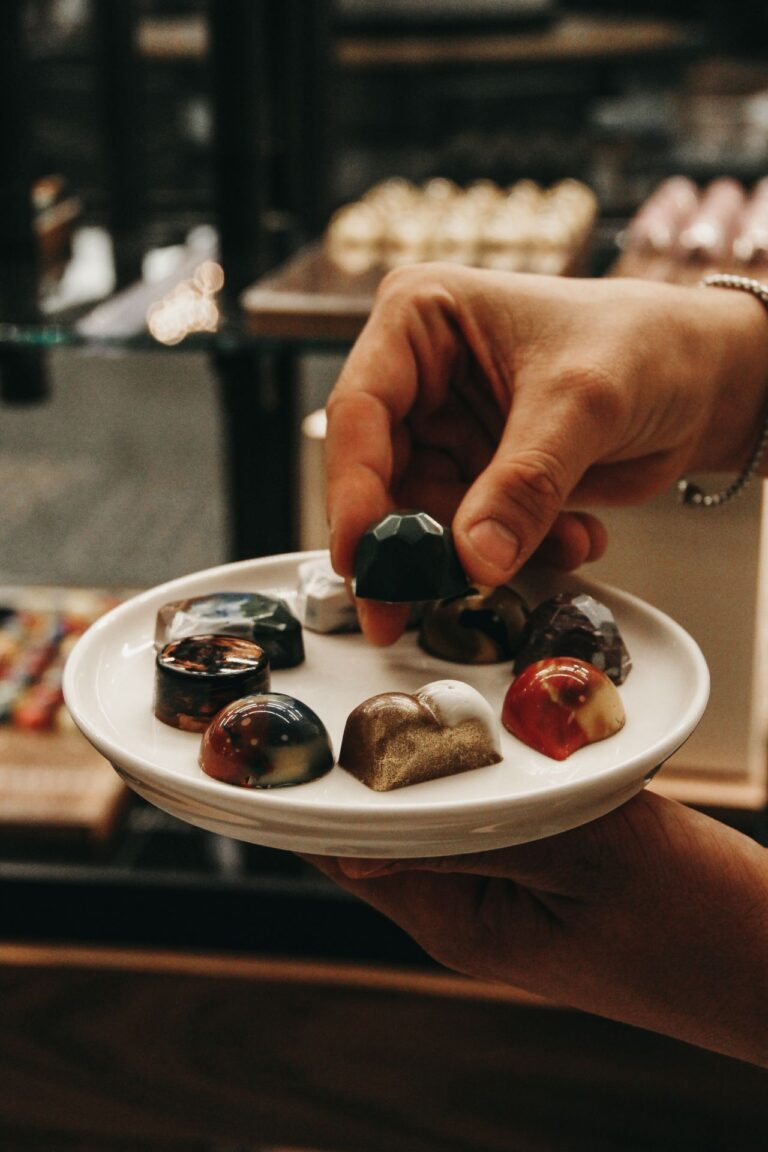 Assorted gourmet chocolates are elegantly presented with a hand showcasing their intricate designs.